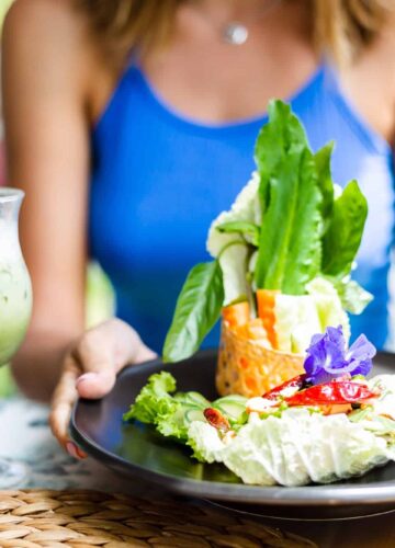 woman in cute blue top having spicy fresh salad with salmon and vegetables